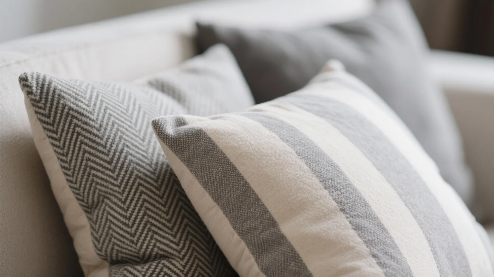 Close up of soft striped and patterned pillows on a beige sofa in a living room