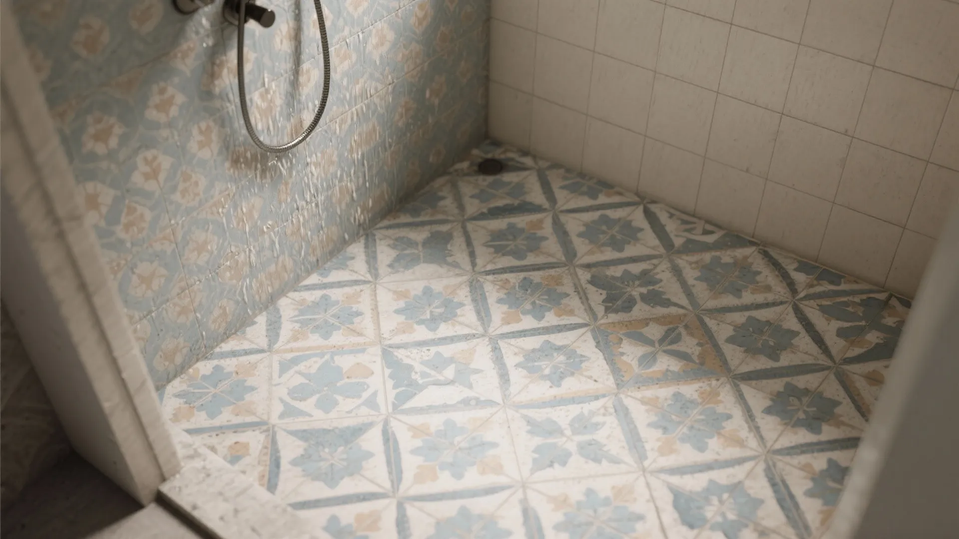Bathroom shower floor with blue and beige patterned tiles and matching wall tiles with water