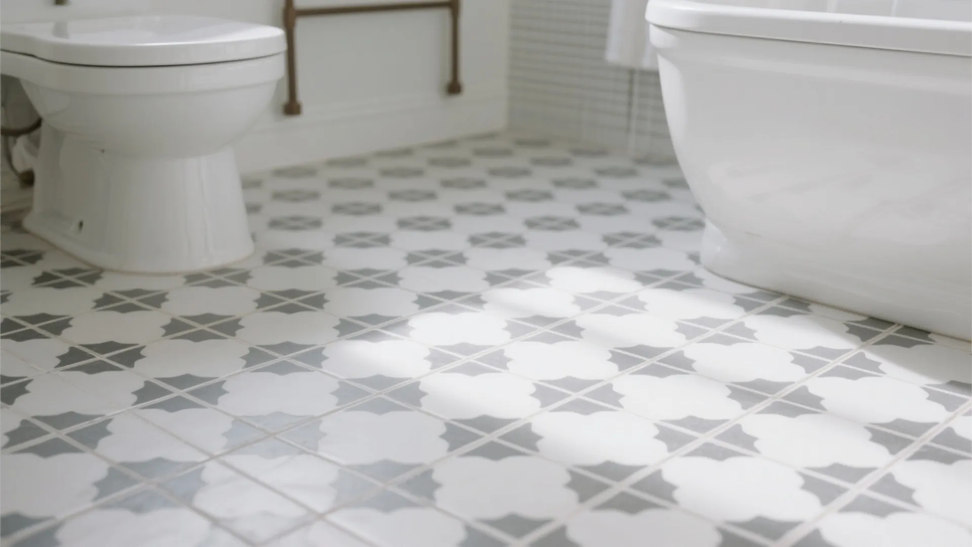 Modern bathroom floor with patterned grey tiles white toilet and bathtub under bright natural light
