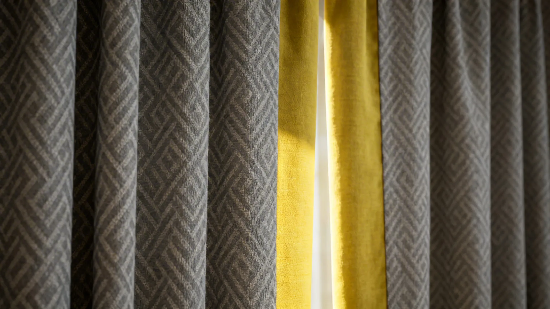 Close-up of subtle gray patterned curtain with solid yellow lining visible