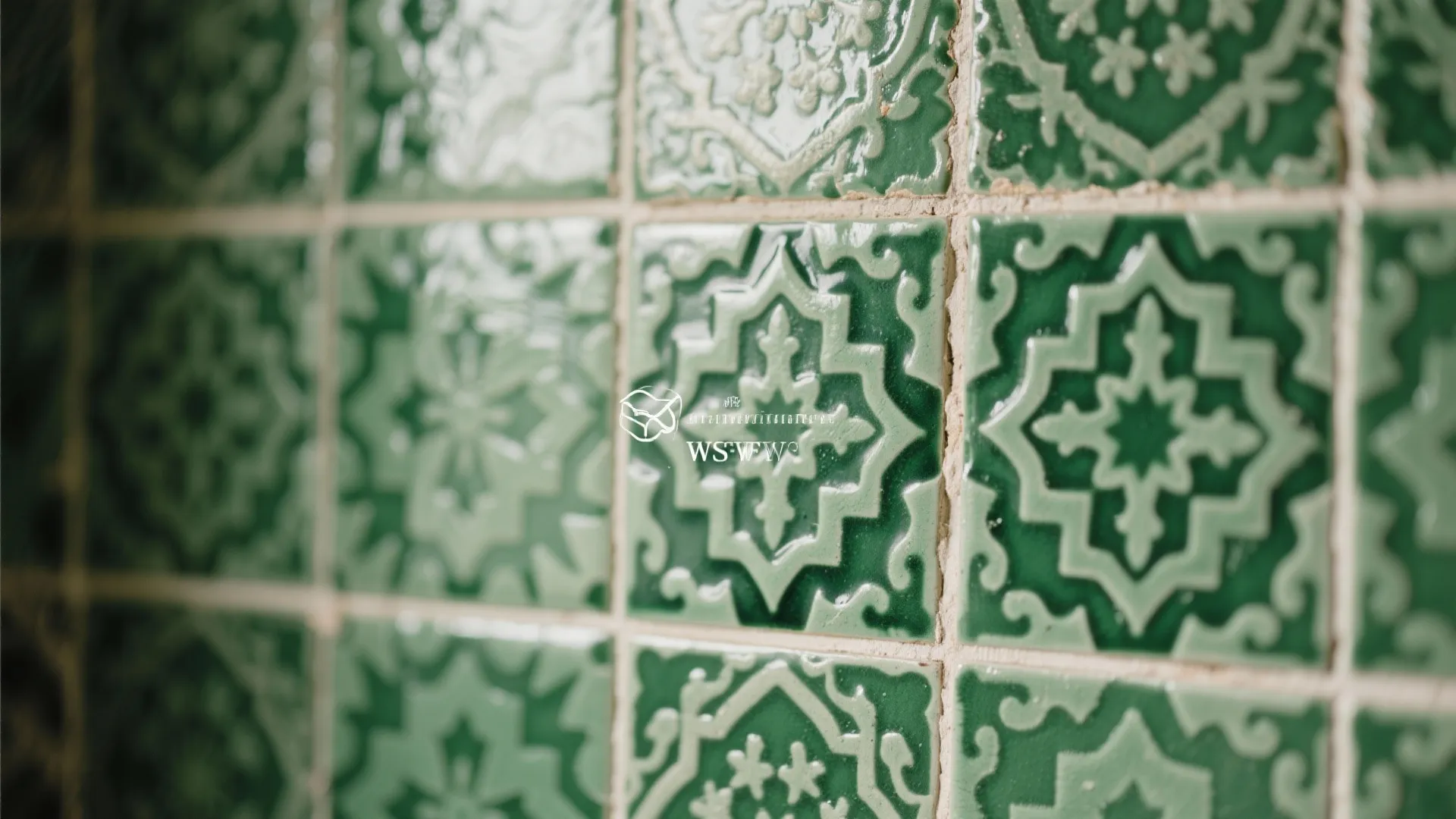 Close up view of green ceramic wall tiles featuring a traditional patterned design and white grout