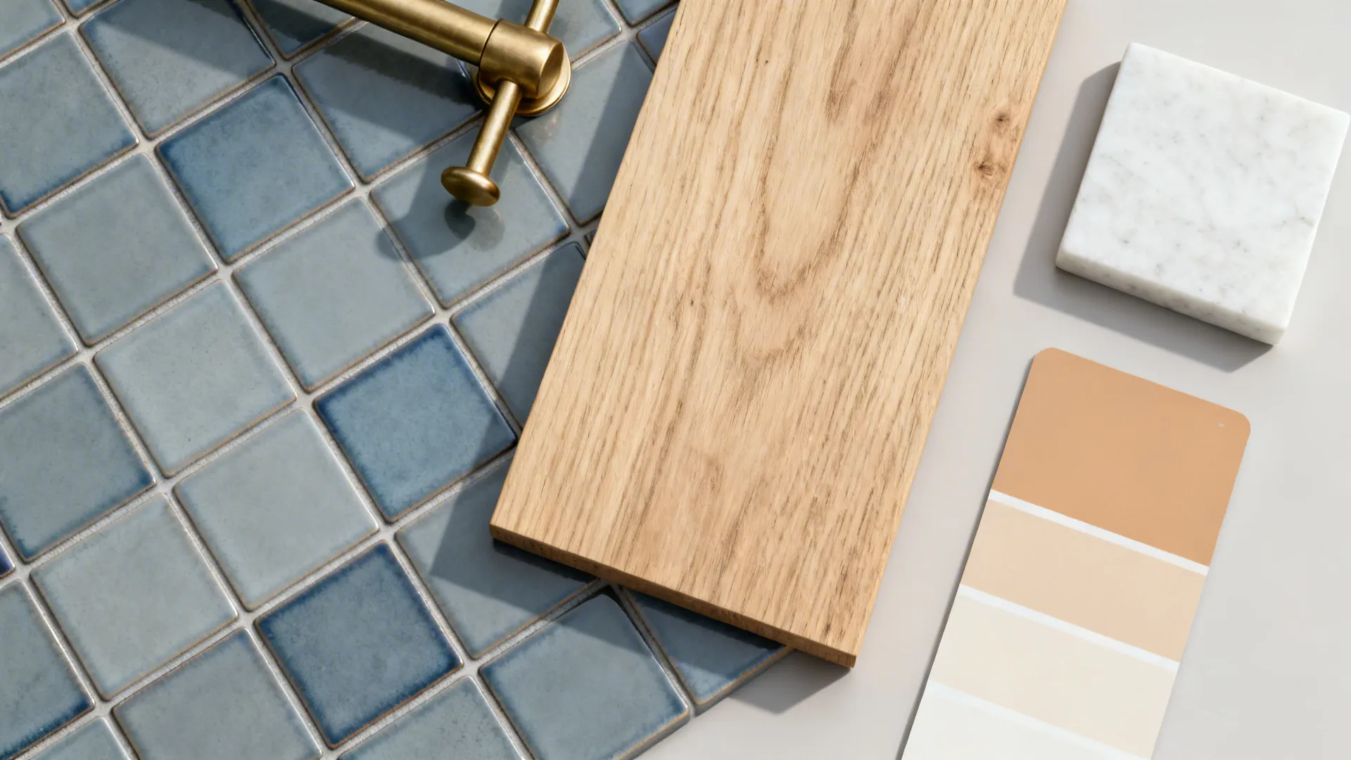 Top-down flatlay of blue-grey patterned tiles with oak, brass, and quartz samples.