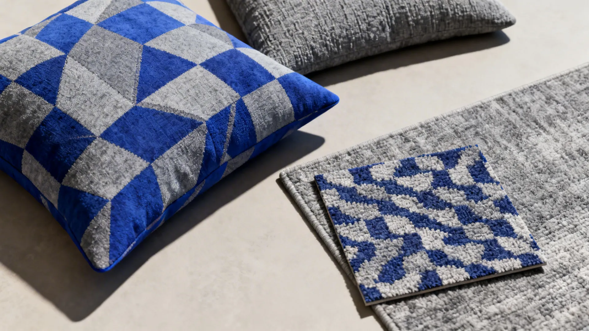 Flatlay of royal blue and grey patterned cushions with rug swatches