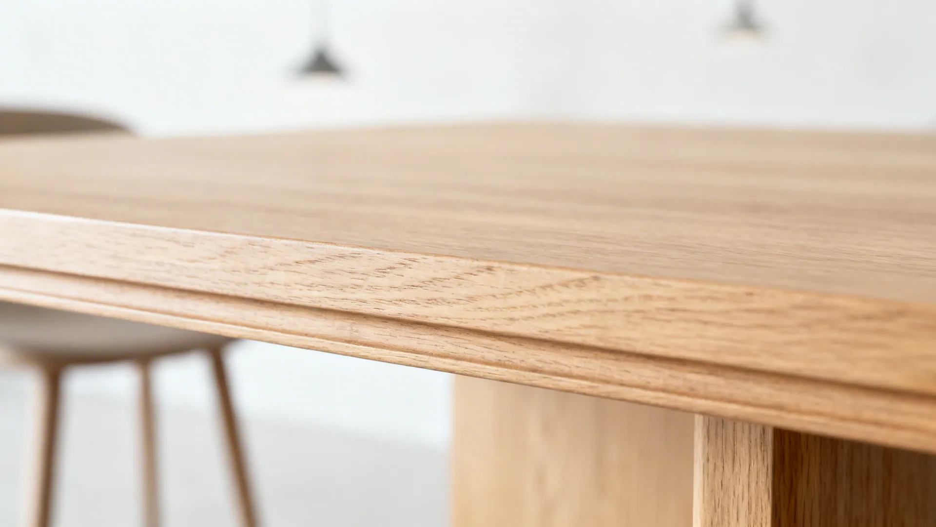 Macro of beveled round table edge in matte light oak with fine grain detail.