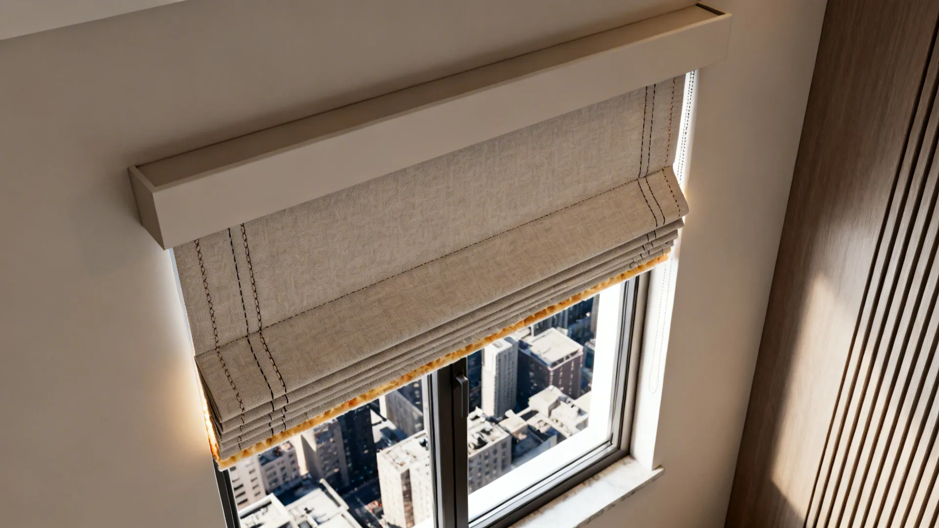 Simple beige fabric window blind covering the top of a window overlooking a big city