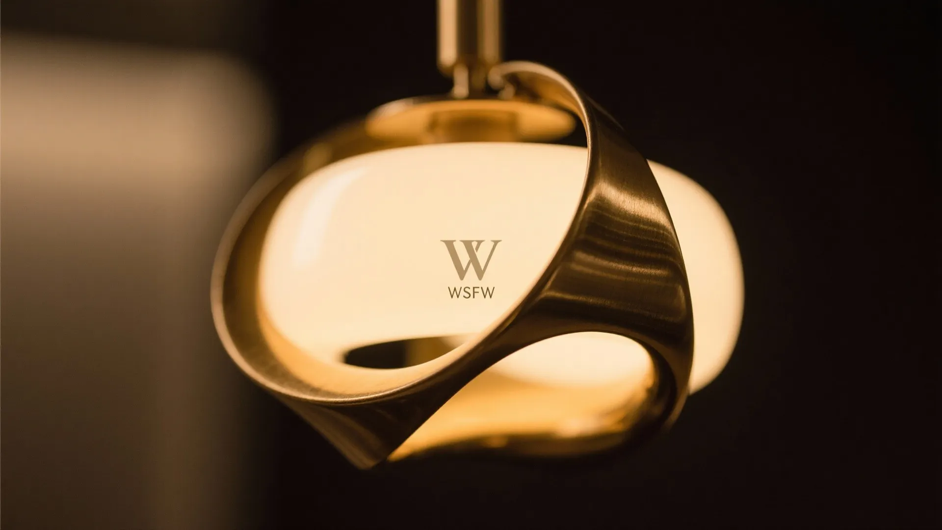 Modern brass ceiling light with a curved metal frame emitting soft warm glow for interiors