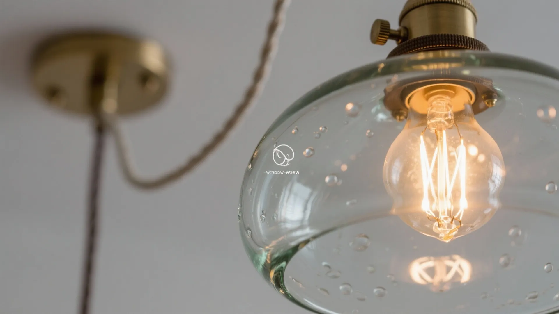 Close up of a glass globe light fixture with a glowing bulb and brass hardware