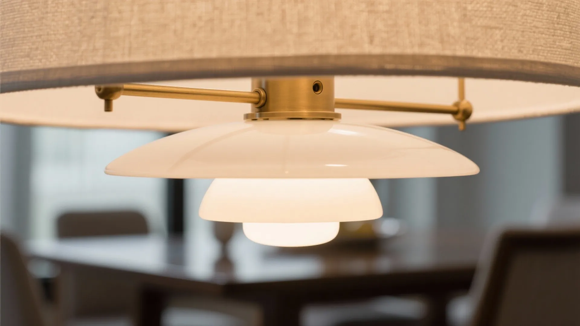 Close up of a modern ceiling light fixture with a white shade and gold metal base