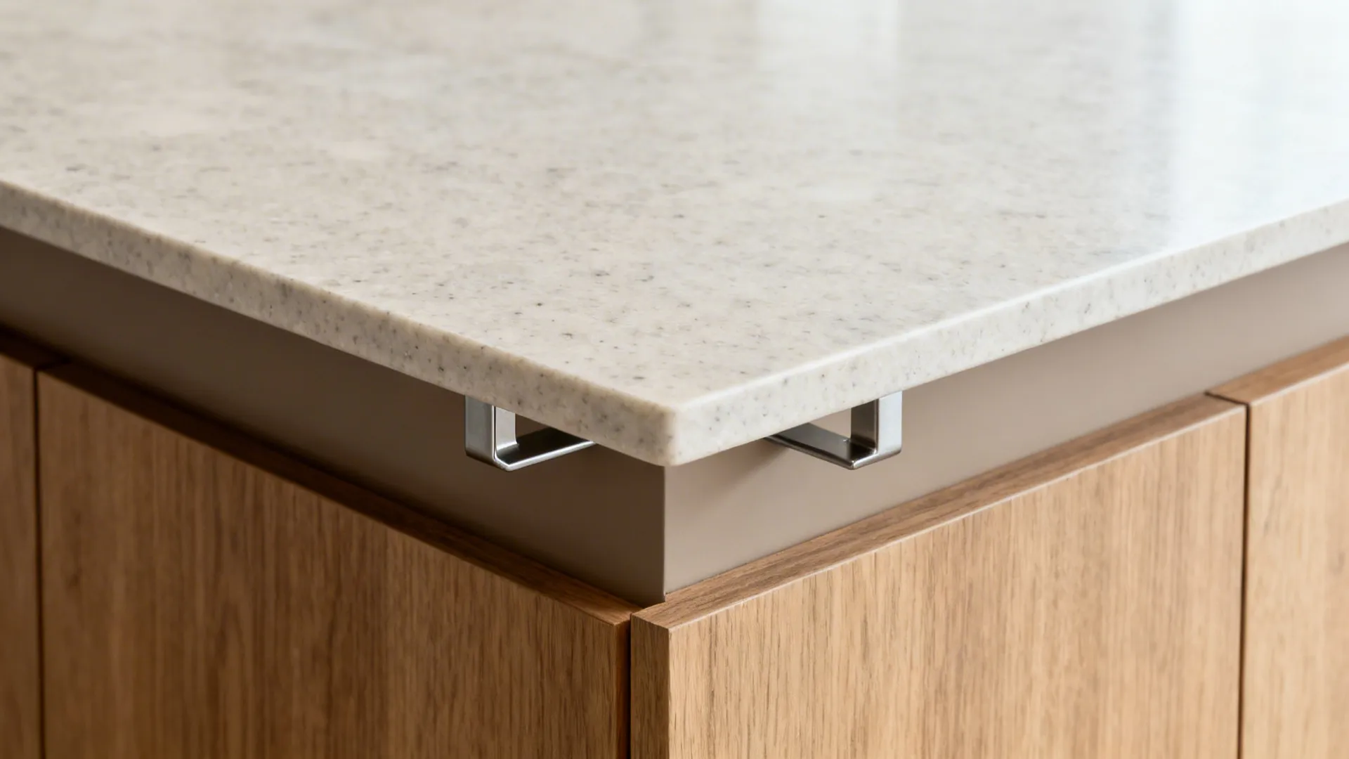 Close-up of metal brackets supporting a marble countertop on a wooden kitchen island with cabinets