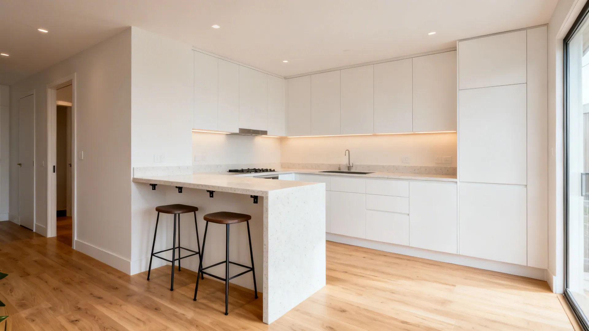 Compact U-shaped kitchen with a slim peninsula and two backless stools under a 12-inch overhang.