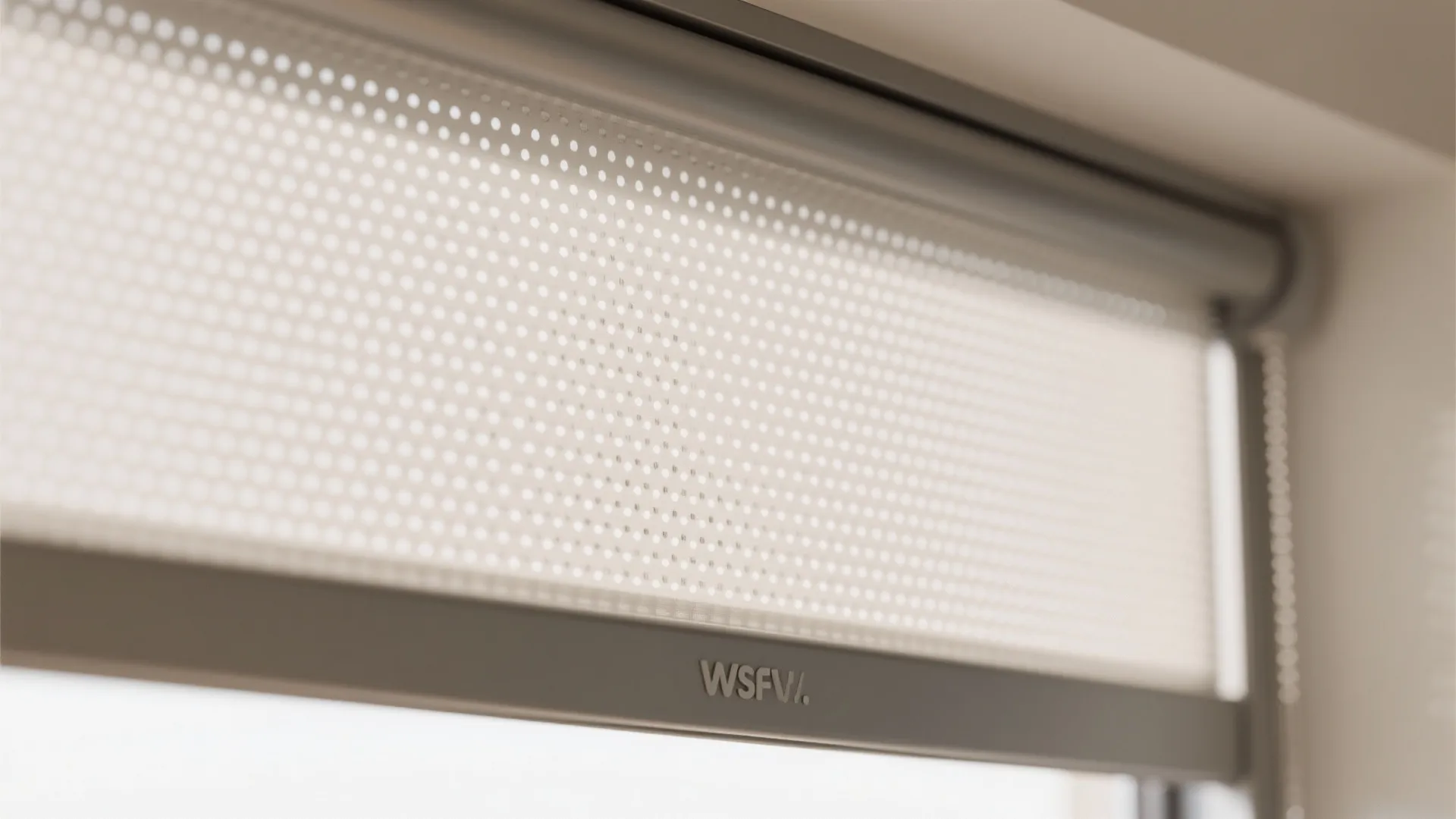 Close up of white perforated window roller blind showing small holes for light and privacy