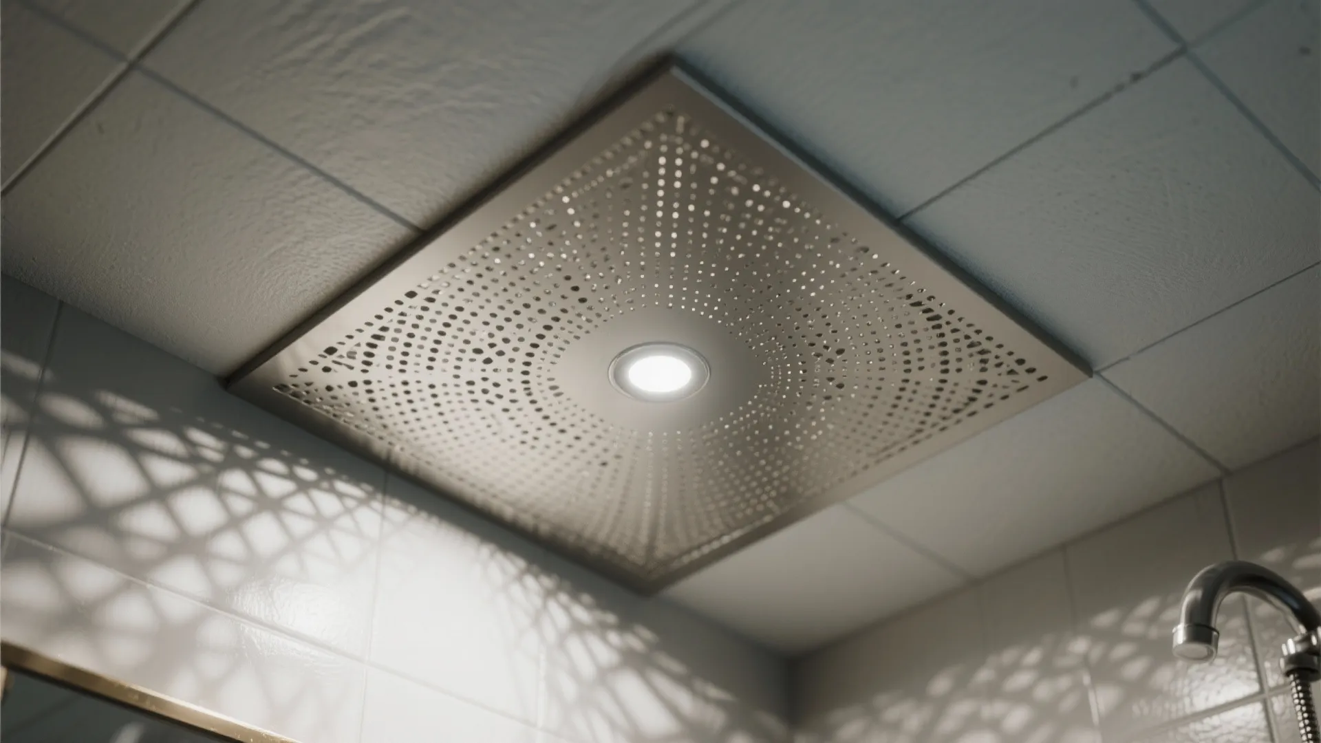 Square metal ceiling panel with tiny holes and a small round light in the middle