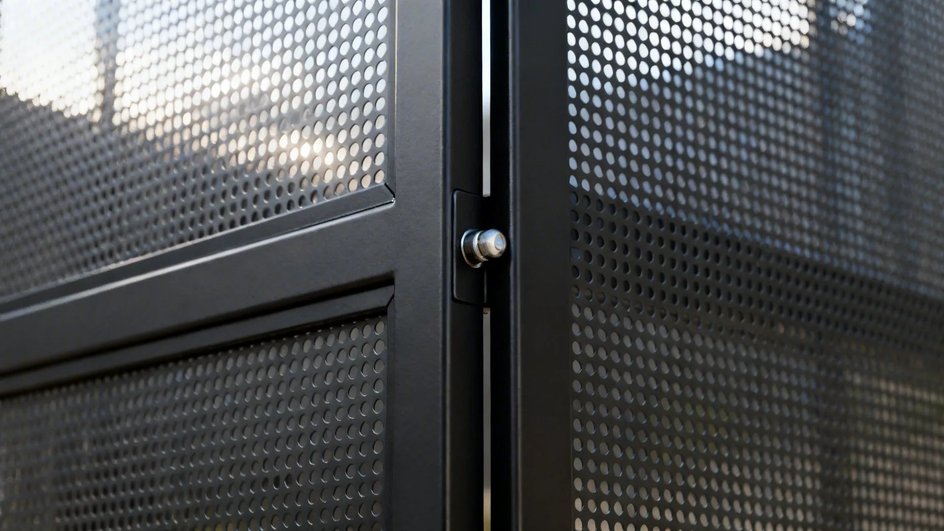 Macro of matte black metal frame and micro-perforated steel panel on a pivot door.