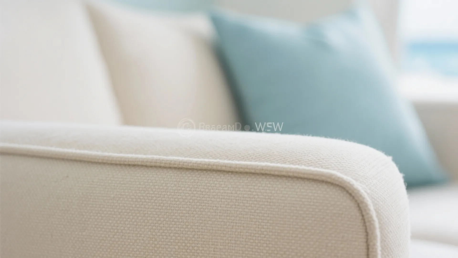 Close up of cream sofa fabric texture with blurry blue and white pillows in background