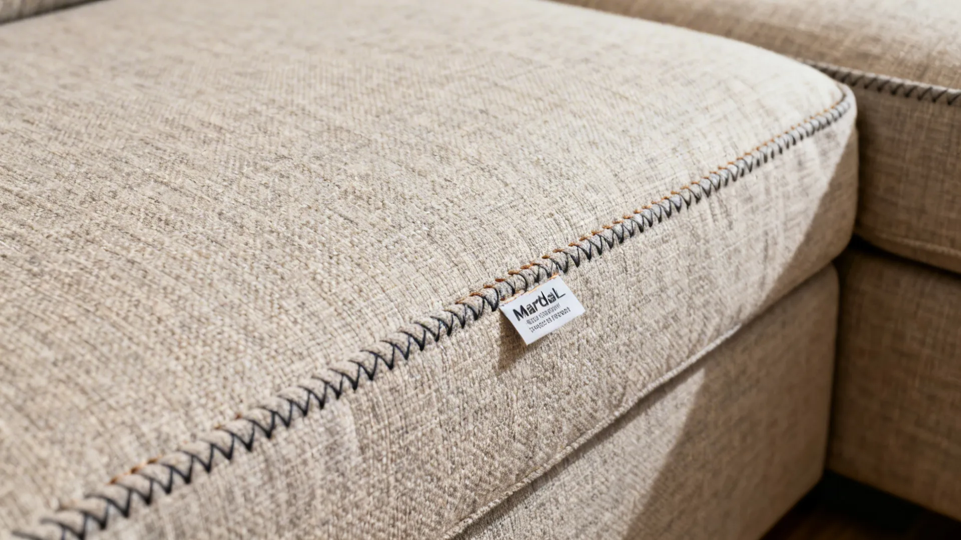 Macro of textured performance fabric and removable slipcover seam on an L-shaped sofa.