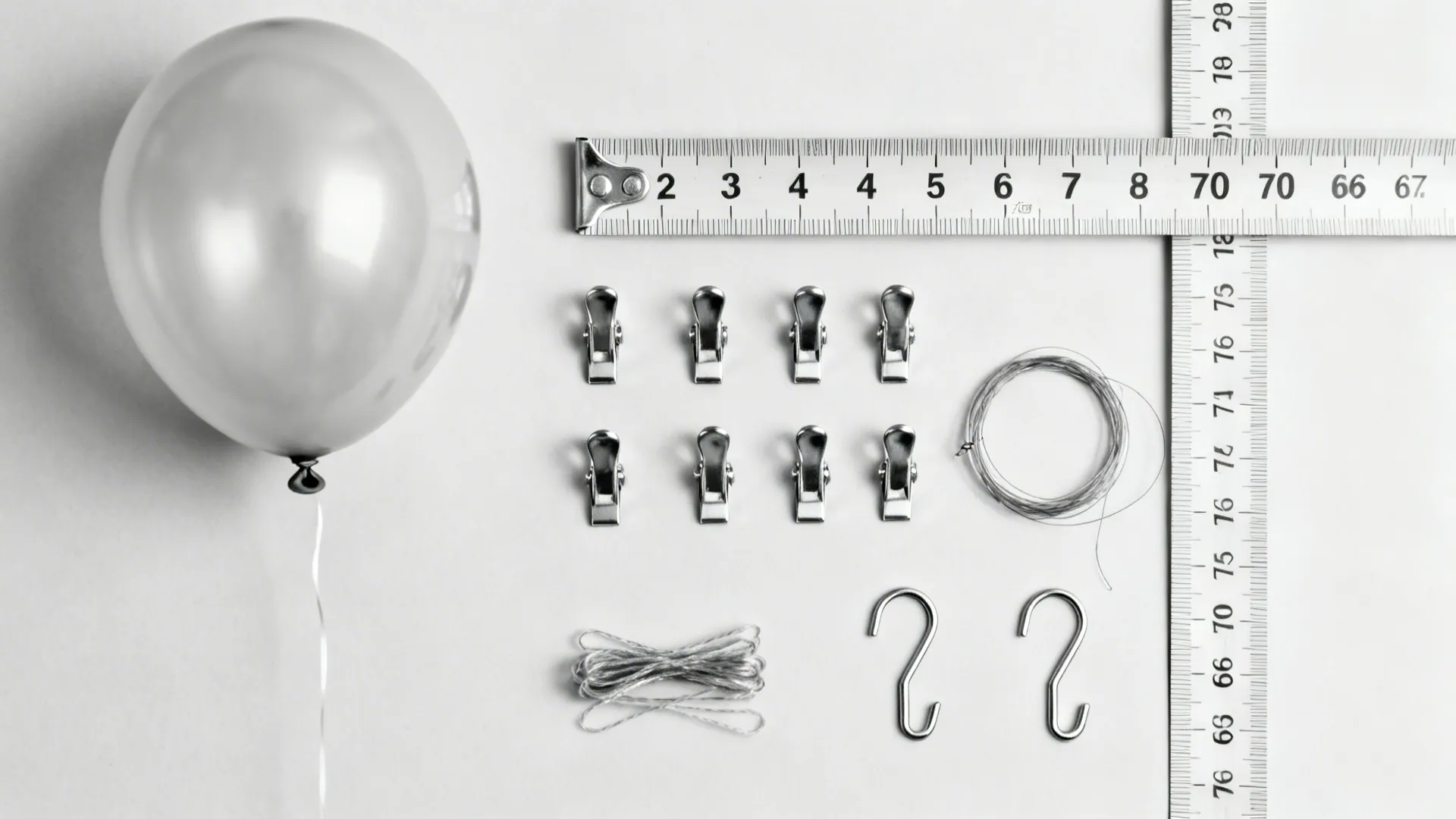 Single balloon measuring tape metal clips wire and hooks placed on a plain white background