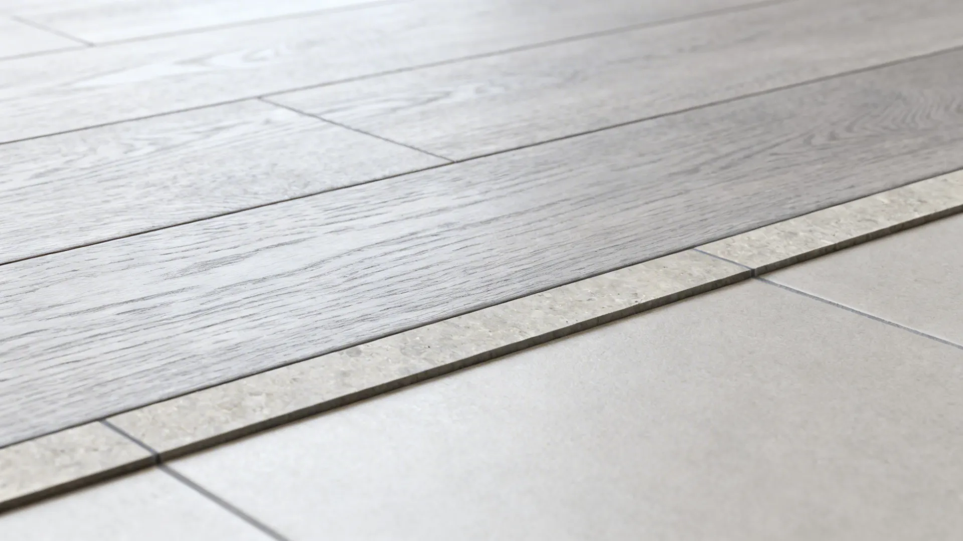 Close-up of light grey planks meeting a slim natural stone border with flush threshold