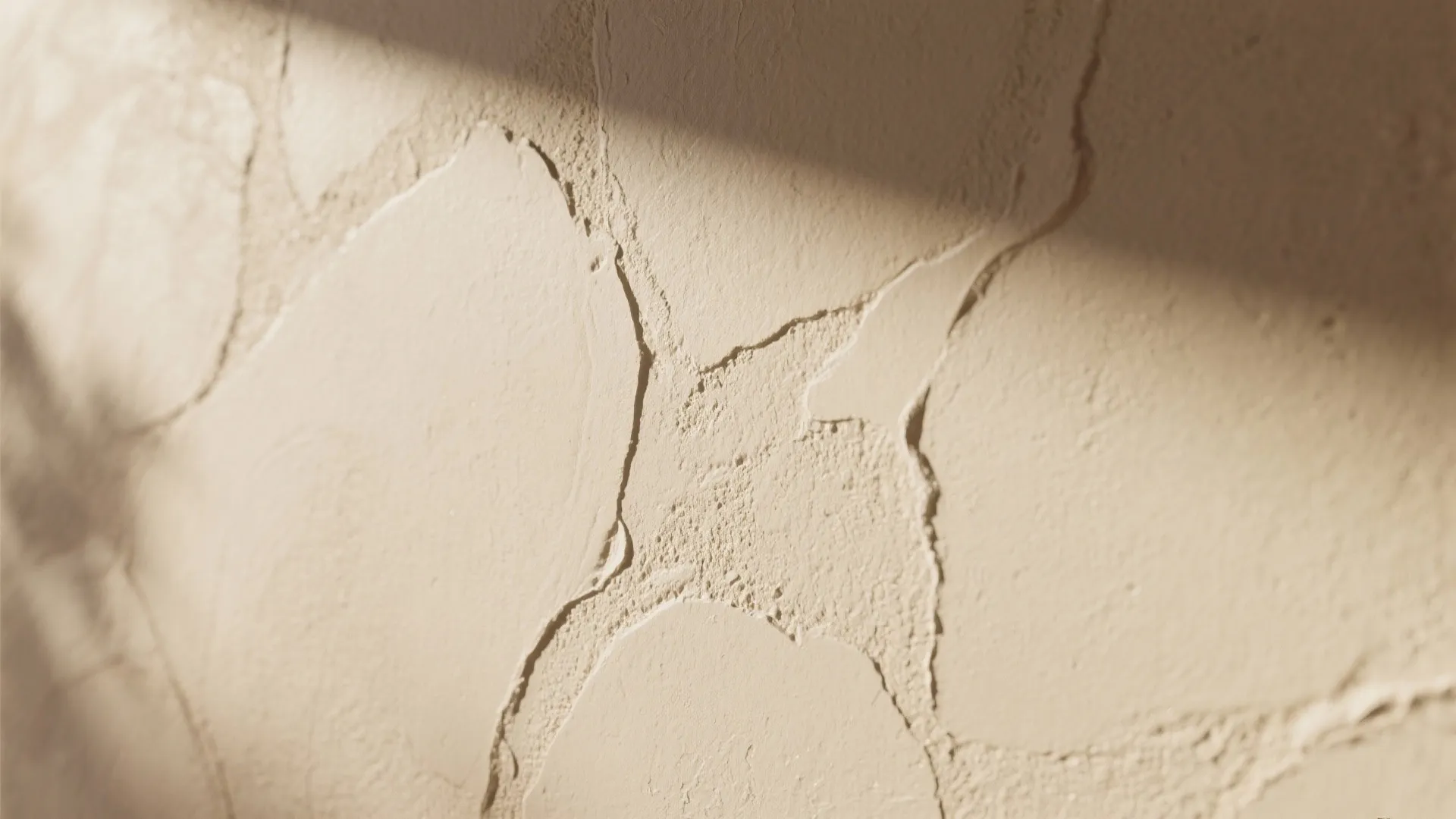 Close up view of cream wall with rough plaster texture and light shadows on surface