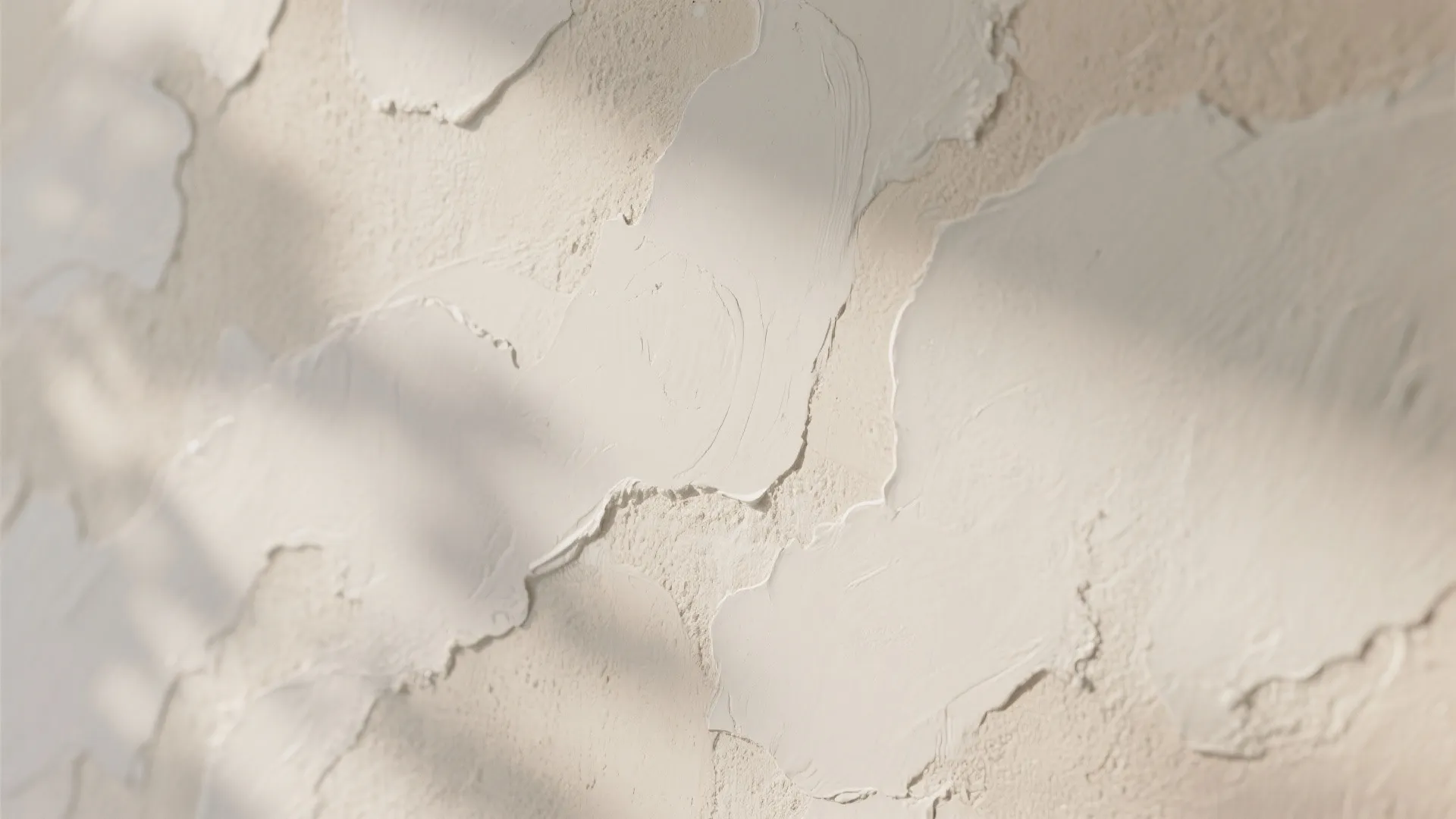 Close up view of cream textured wall paint with soft shadows and artistic hand applied finish