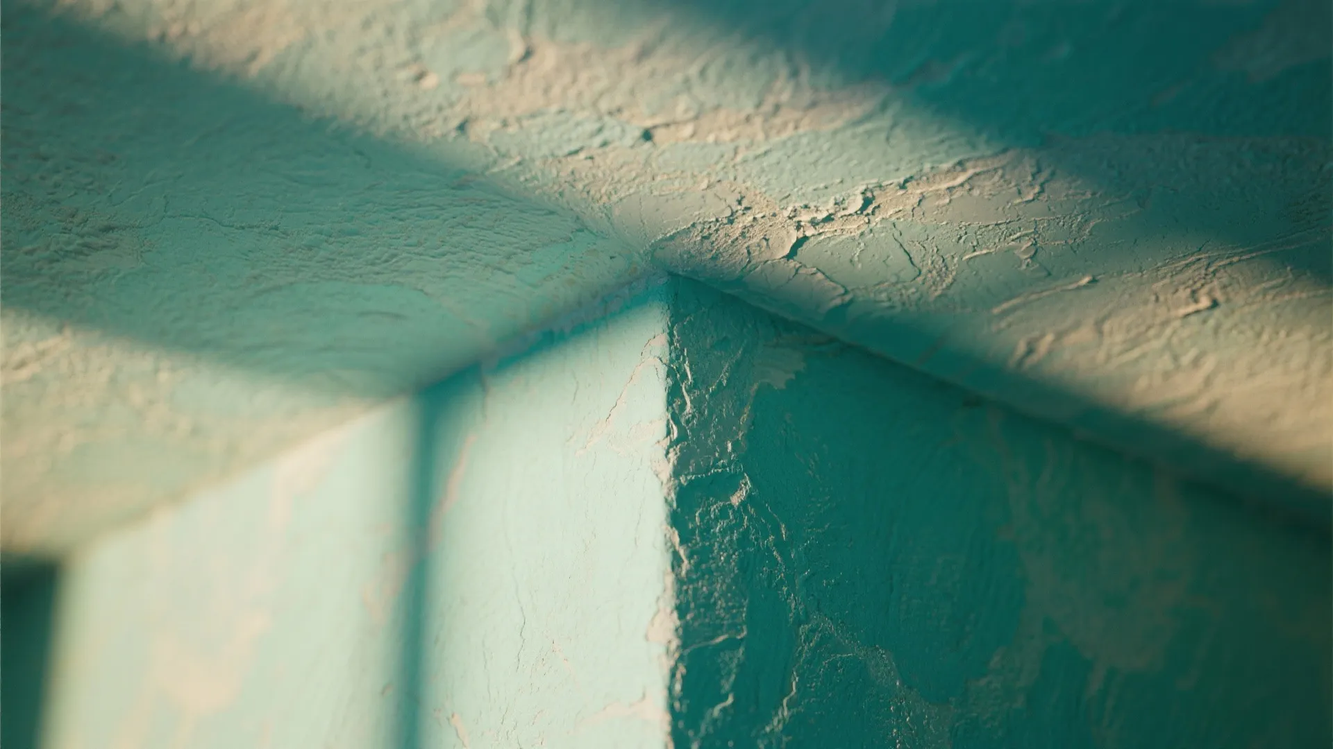 Close up of a wall corner showing light blue textured wall paint with bright shadows