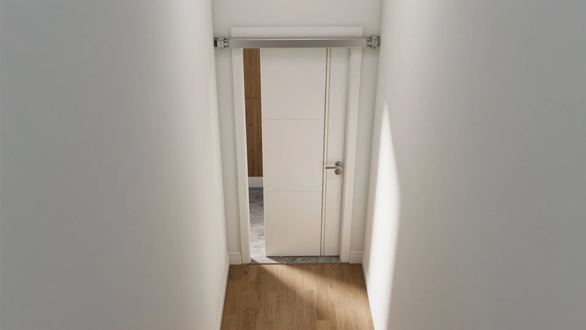 Modern white sliding door installed on a metal track between white walls and wooden flooring