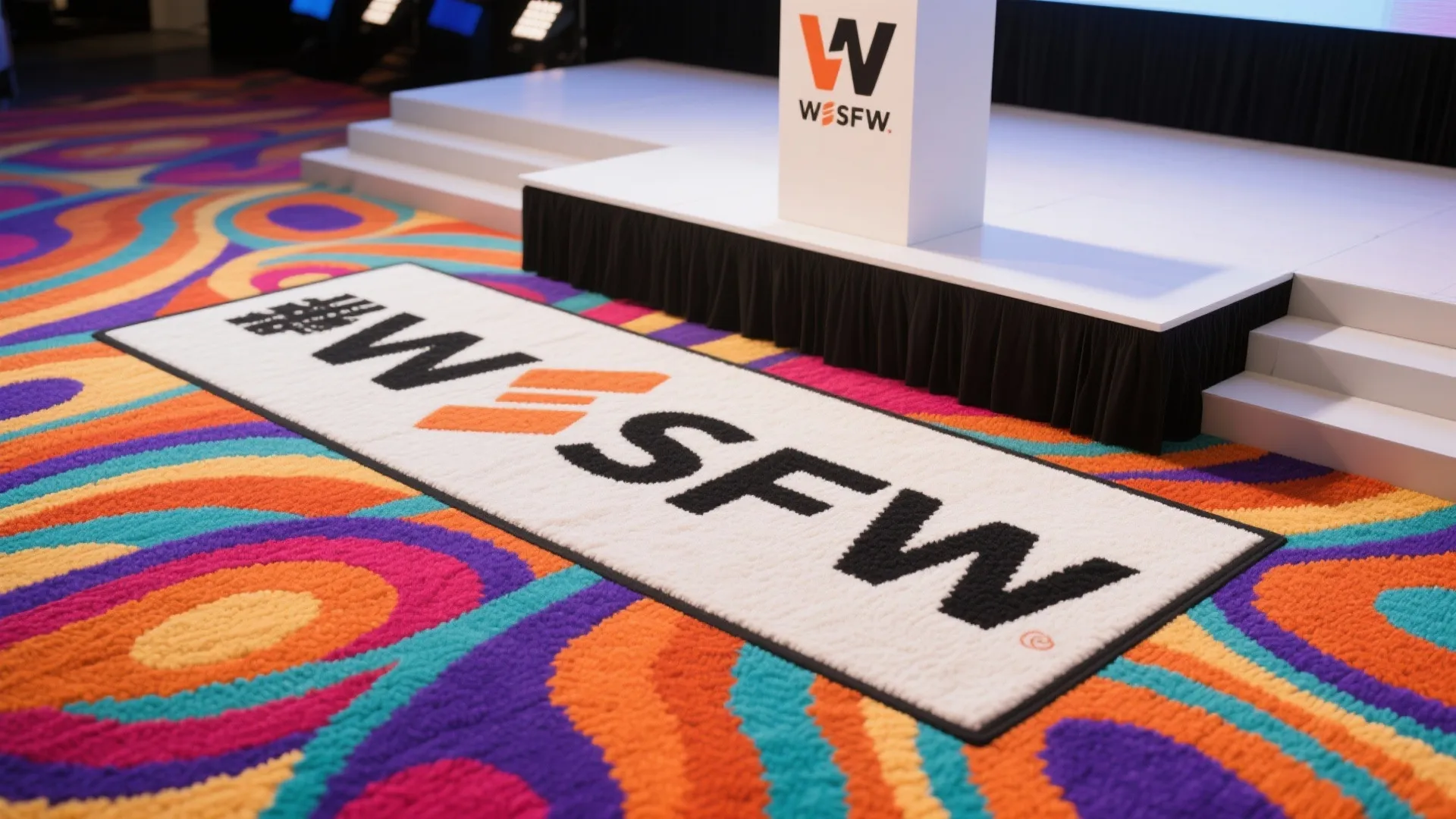 Colorful patterned carpet with a white logo rug placed in front of a white stage