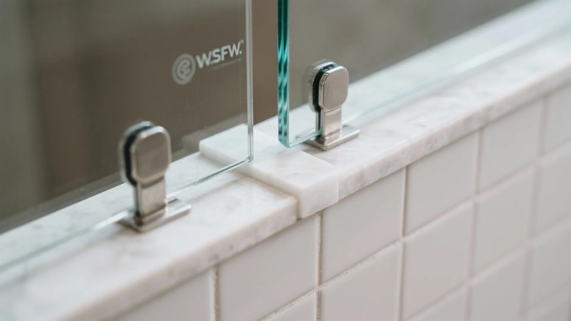 Close up view of glass shower panels installed on top of white marble wall tiles