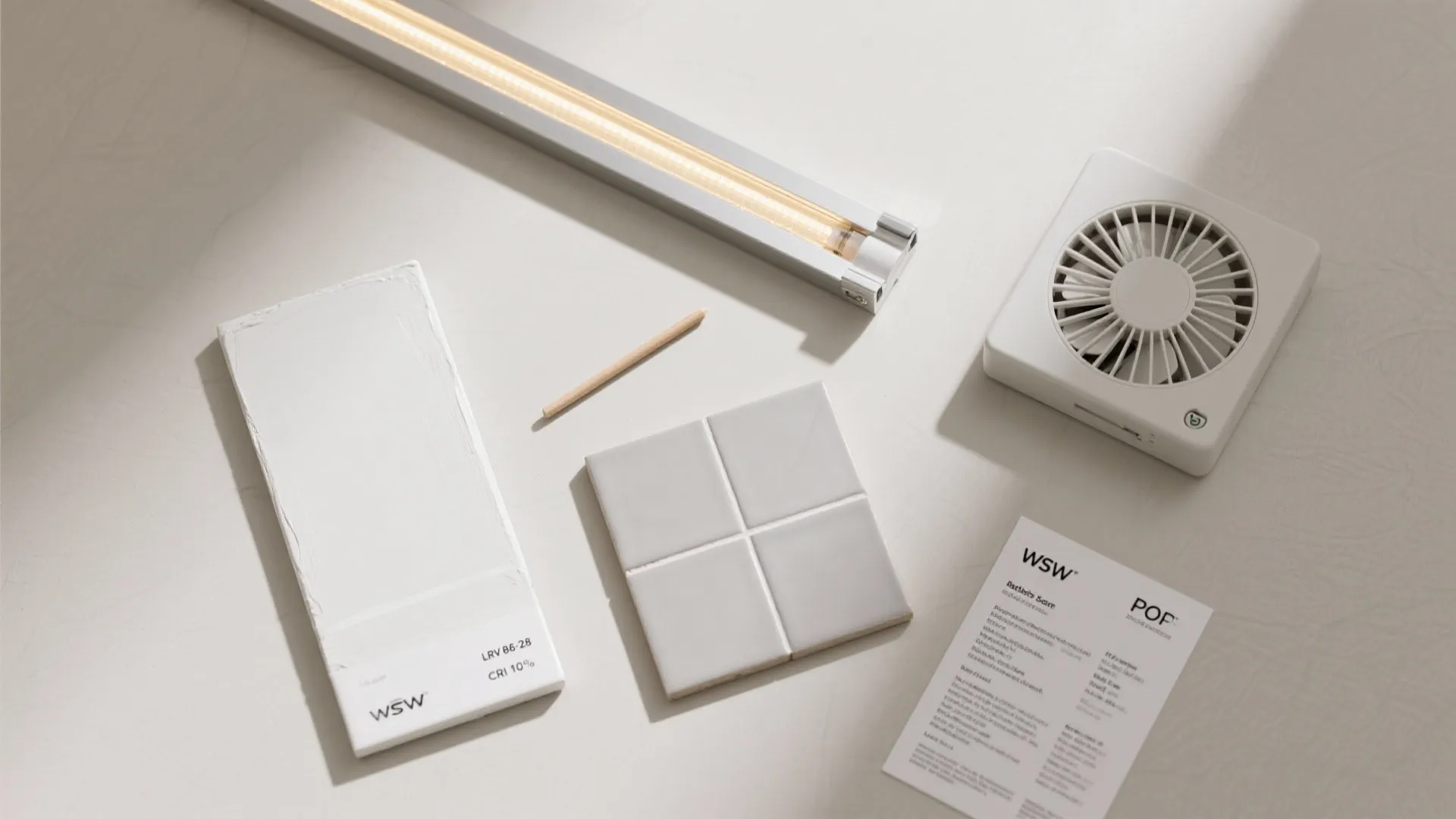 Interior design materials including light fixture, white sample board, grey tiles, and small white fan