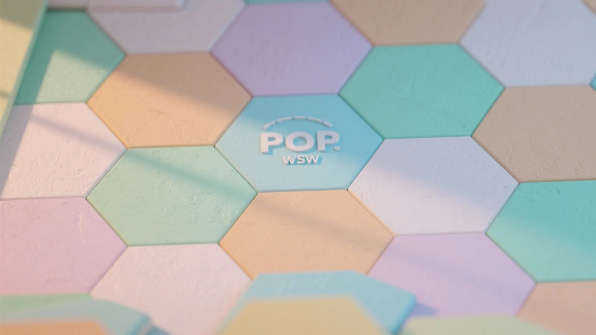 Pastel hexagonal floor tiles in blue pink and orange with pop logo under natural sunlight