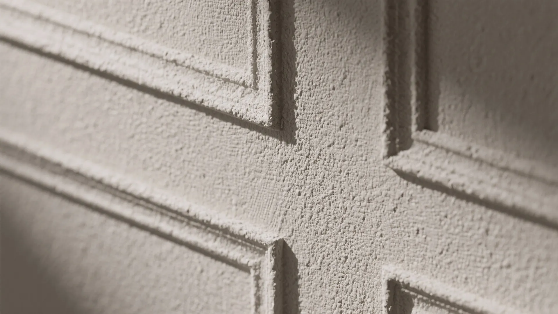 Close up of a rough white wall panel with rectangular shapes and soft shadows from lighting