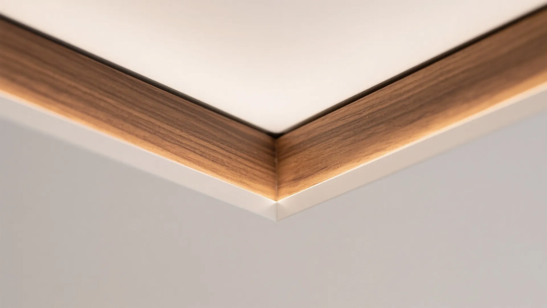 Close up view of wood trim corner with hidden light fixture on a white ceiling