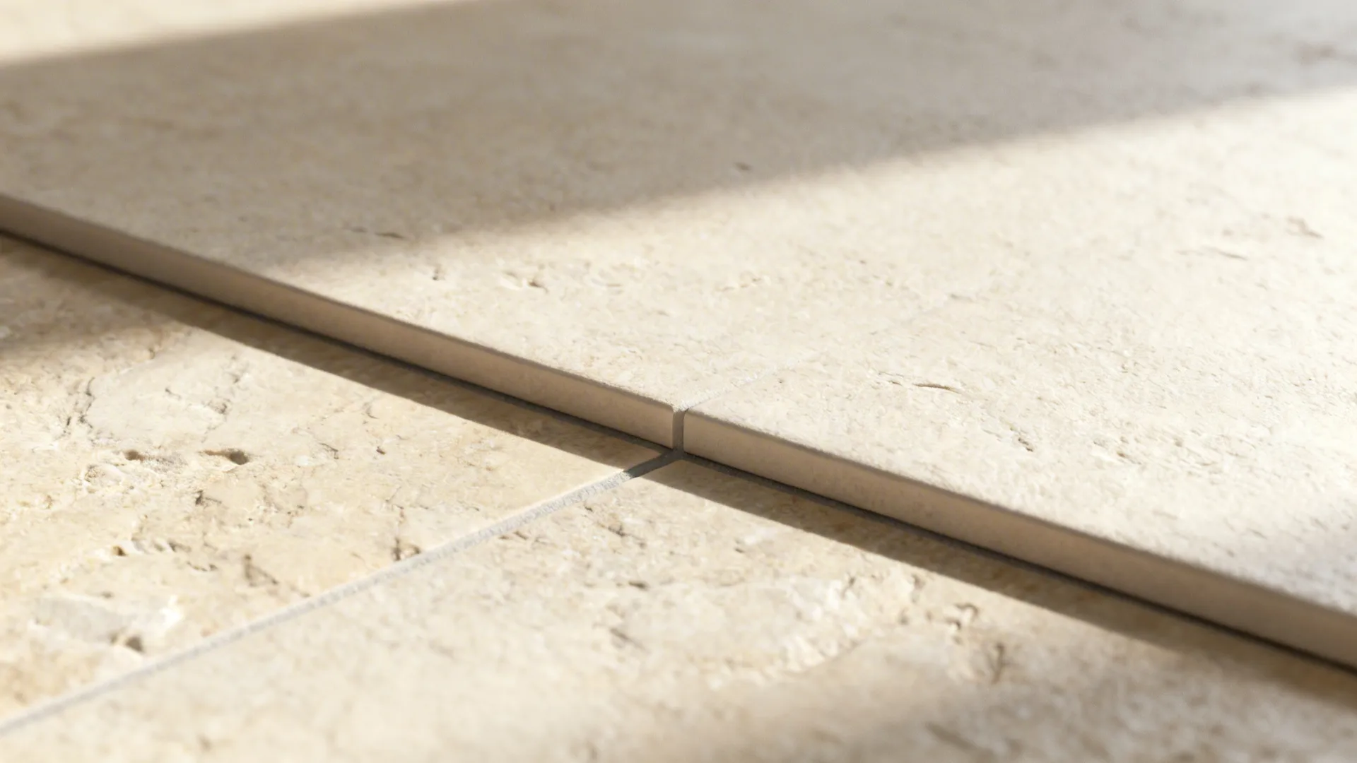 Macro of matte limestone-look porcelain tile with a tight grout joint.