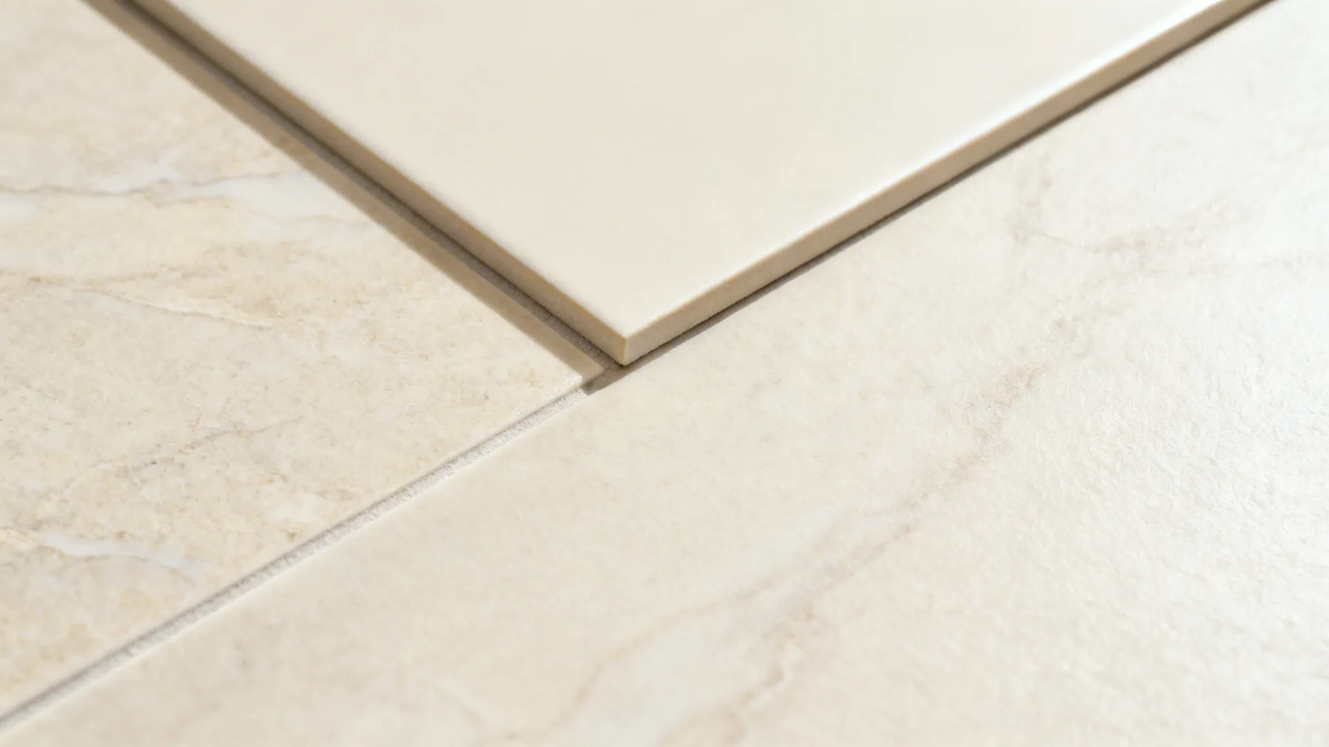 Close-up of cream porcelain slab with rectified edge and thin grout line.