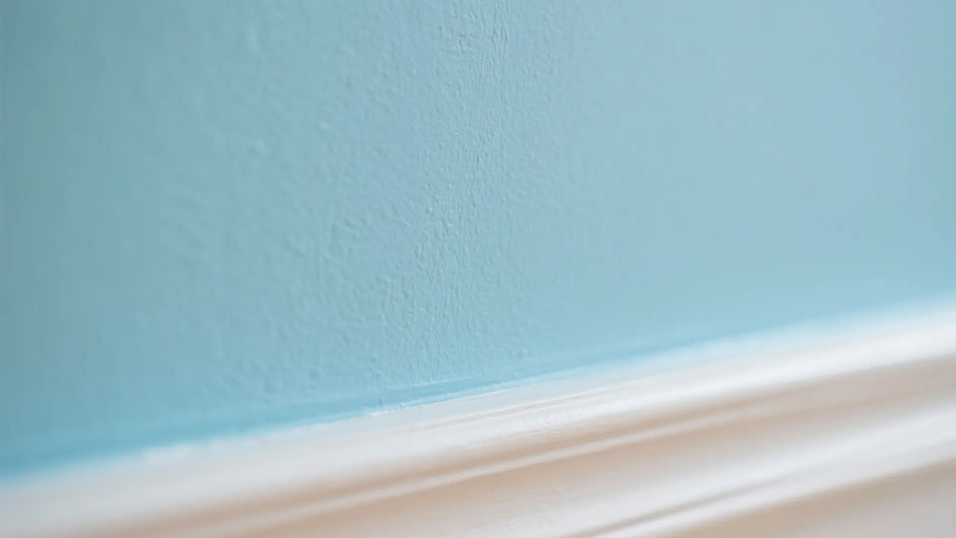 Macro of powder blue wall meeting warm white trim under soft daylight.