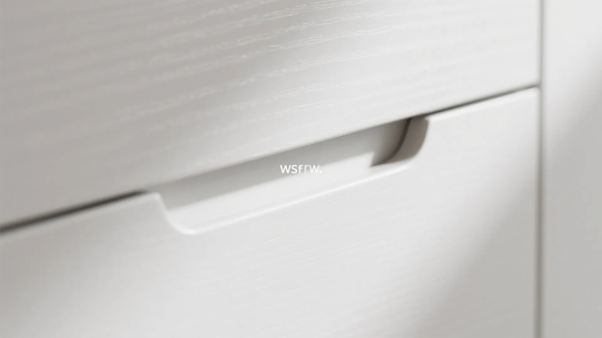 Close-up of a white cabinet drawer with a sleek integrated handle and subtle wood texture