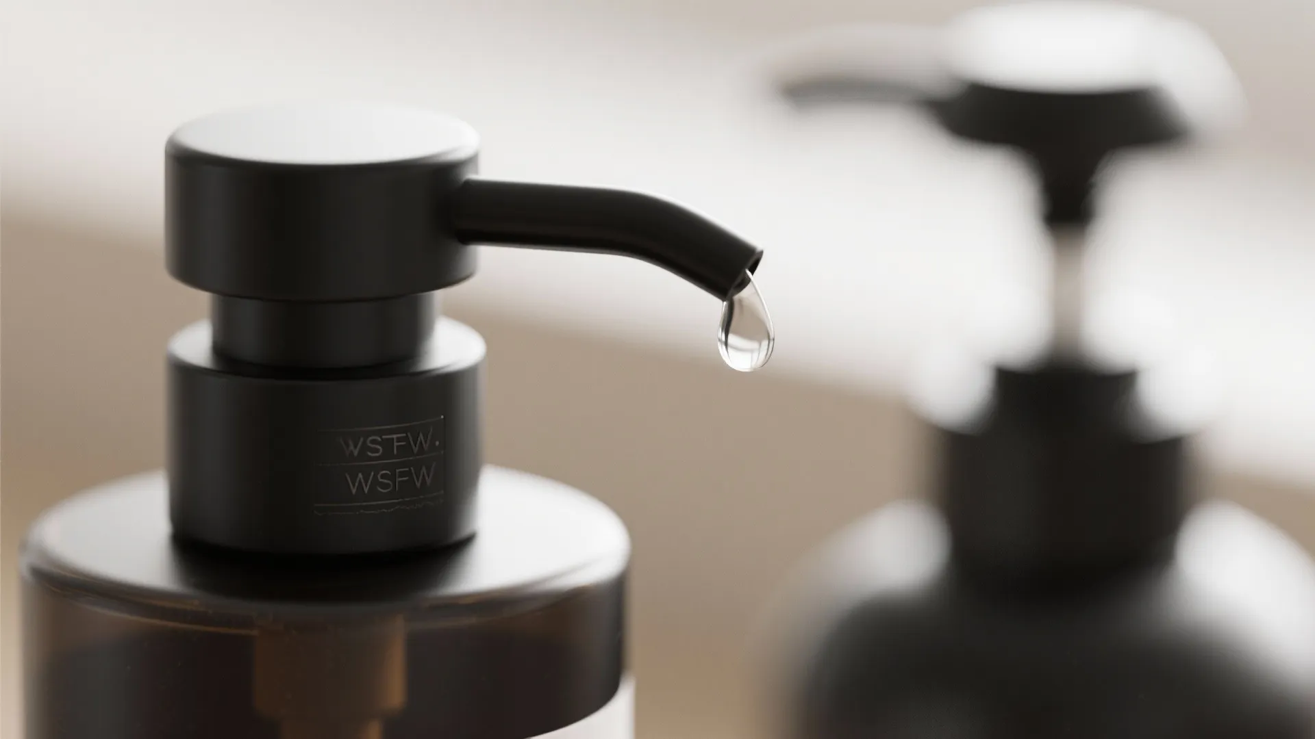 Close-up of a matte black pump head dispensing a drop of soap with subtle engraving visible