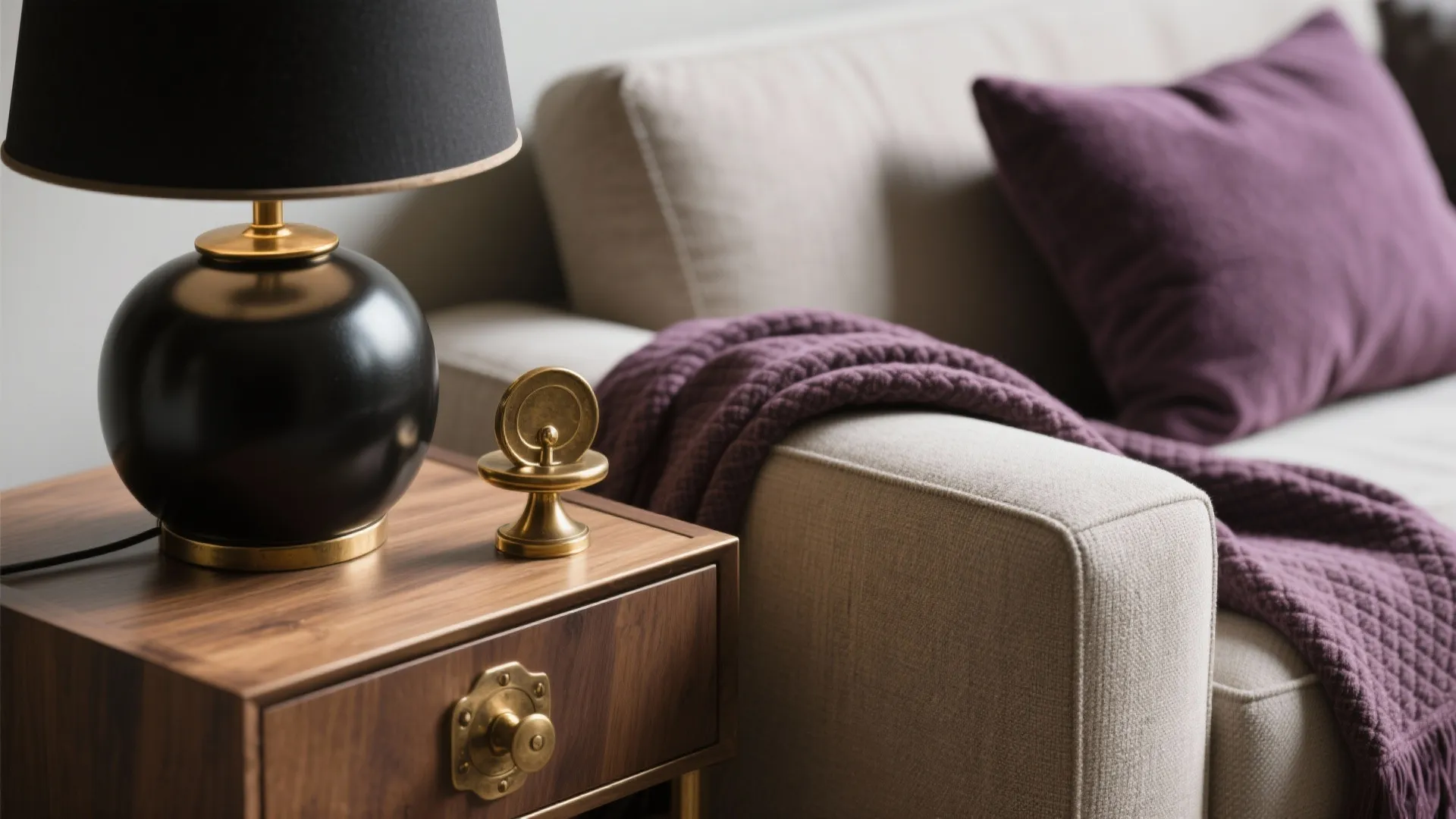 Close up of black table lamp on wooden cabinet next to sofa with purple pillow