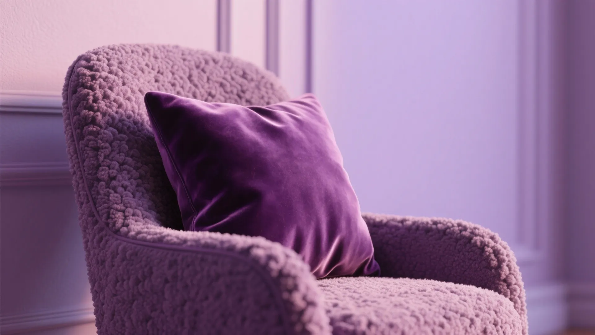 Velvet cushion and boucle chair against an eggshell purple wall showing detailed textile textures and finishes.