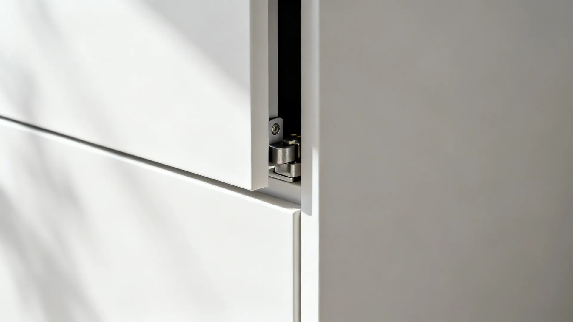Close-up of a push-to-open matte white cabinet with precision hardware.