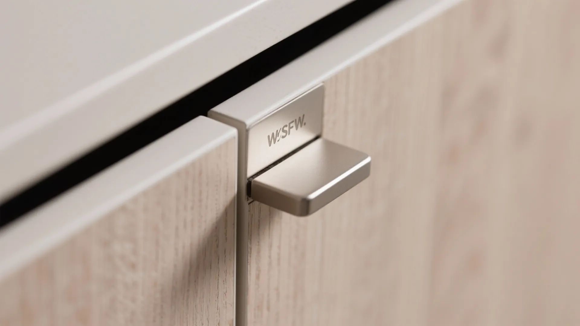 Close-up of silver metal cabinet handle on light wood furniture with a modern minimalist design