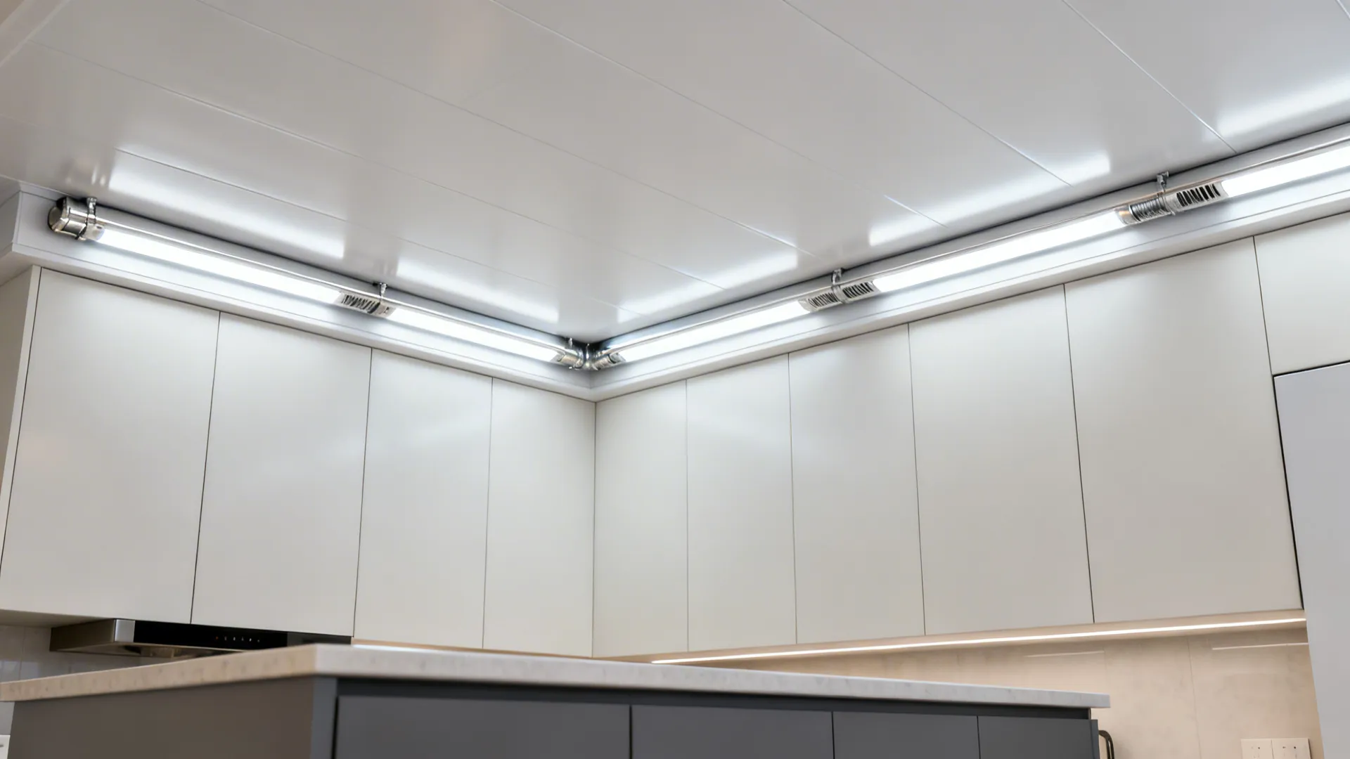 Satin PVC ceiling panels with an LED-lit soffit creating even kitchen light.