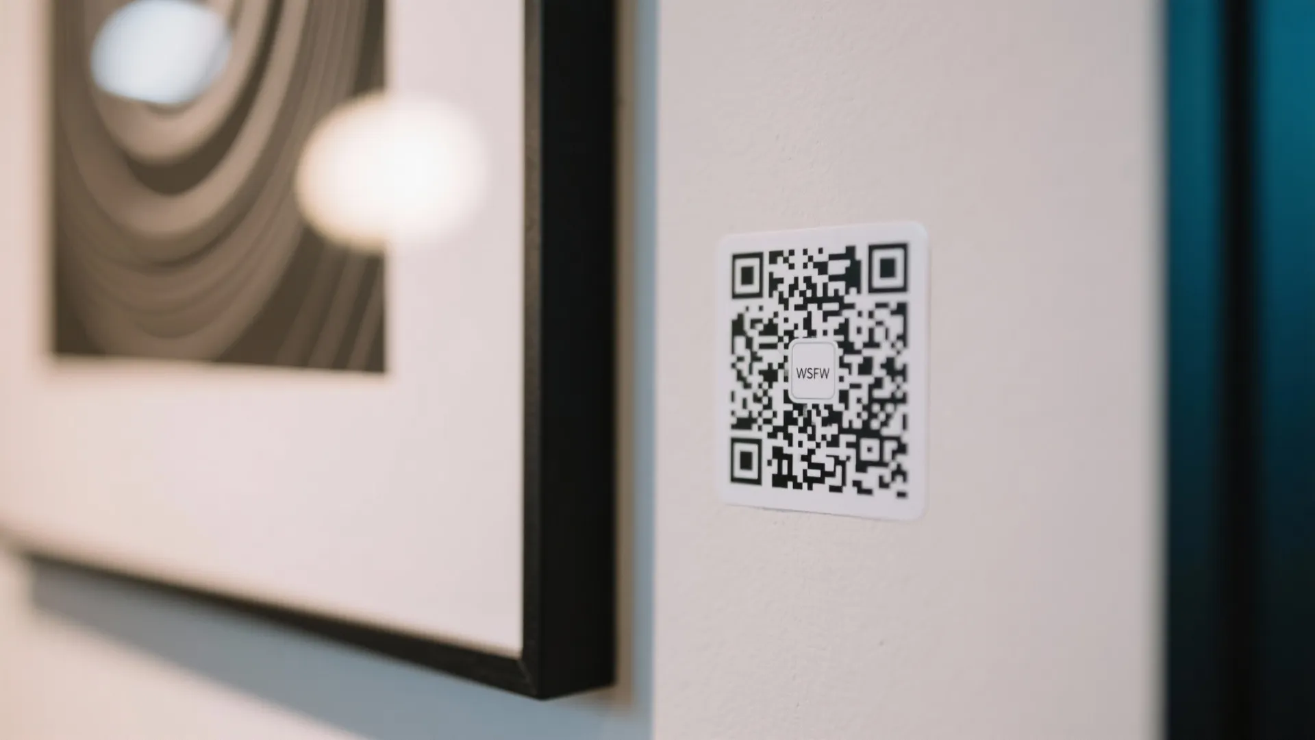 QR code sticker next to framed artwork on a wall magazine