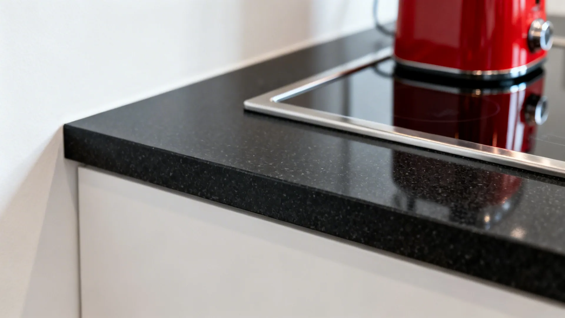 Black quartz counters with white walls and a red statement appliance
