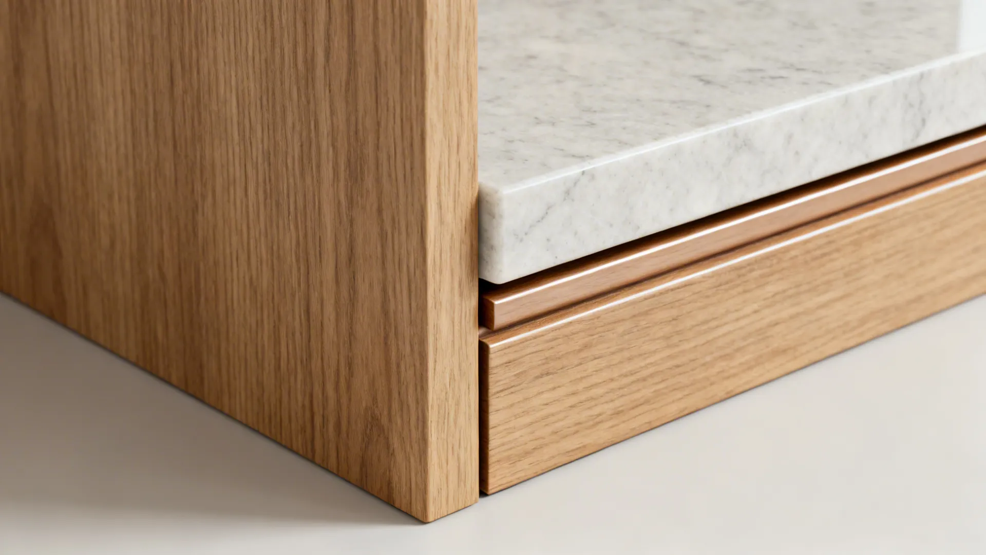 Close-up of engineered quartz counter meeting oak veneer with a slim toe-kick.