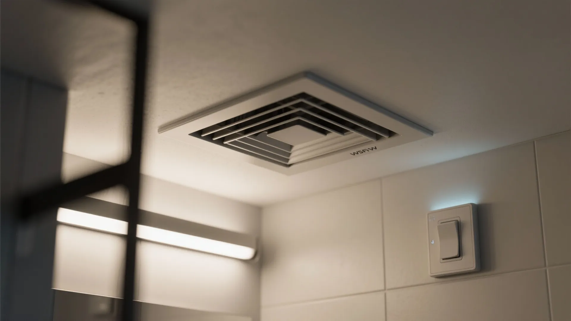 Close up of a square white ceiling exhaust fan and light switch on tiled wall