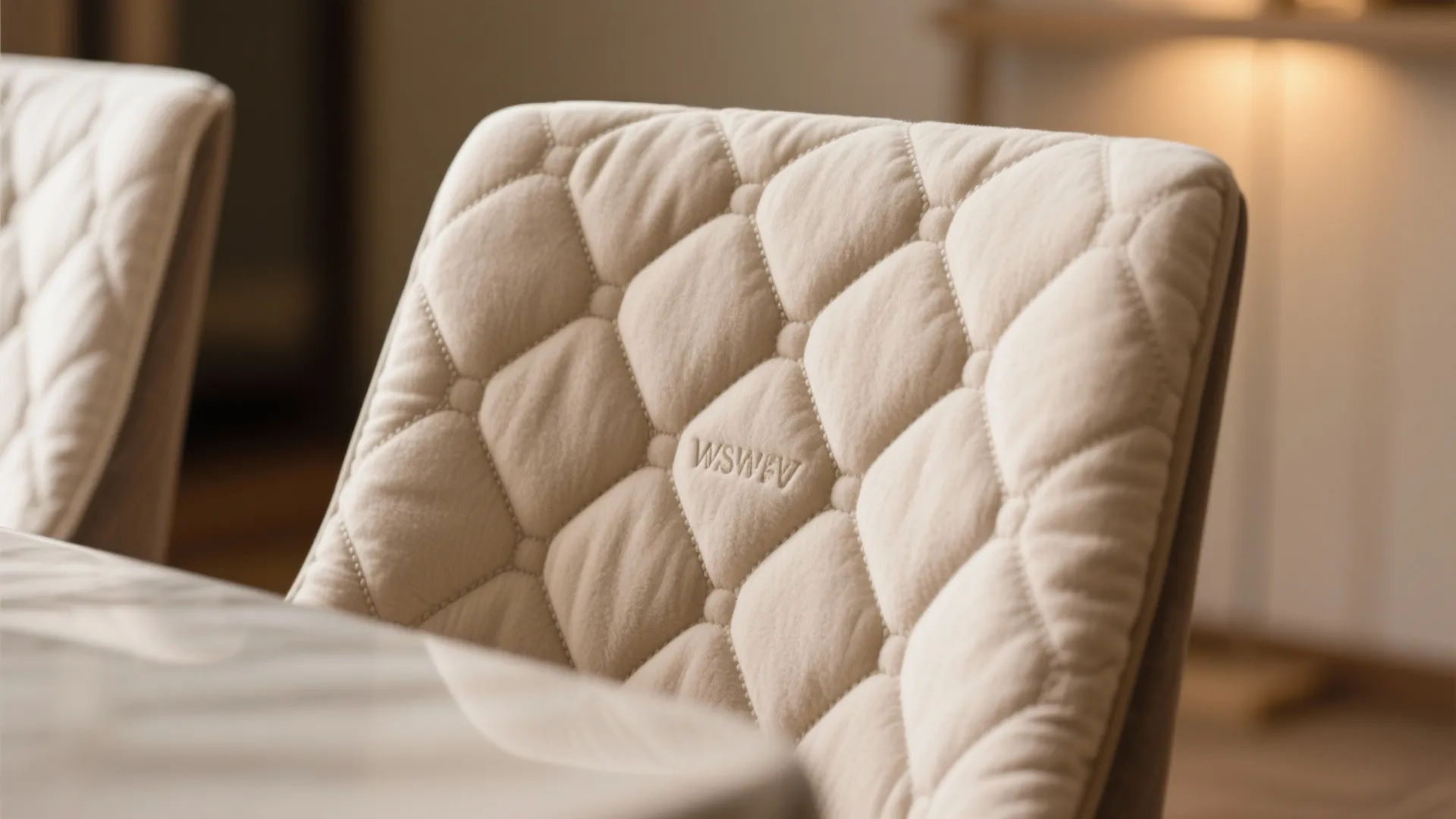 Close up view of a soft beige quilted chair cover with diamond pattern and metal buttons