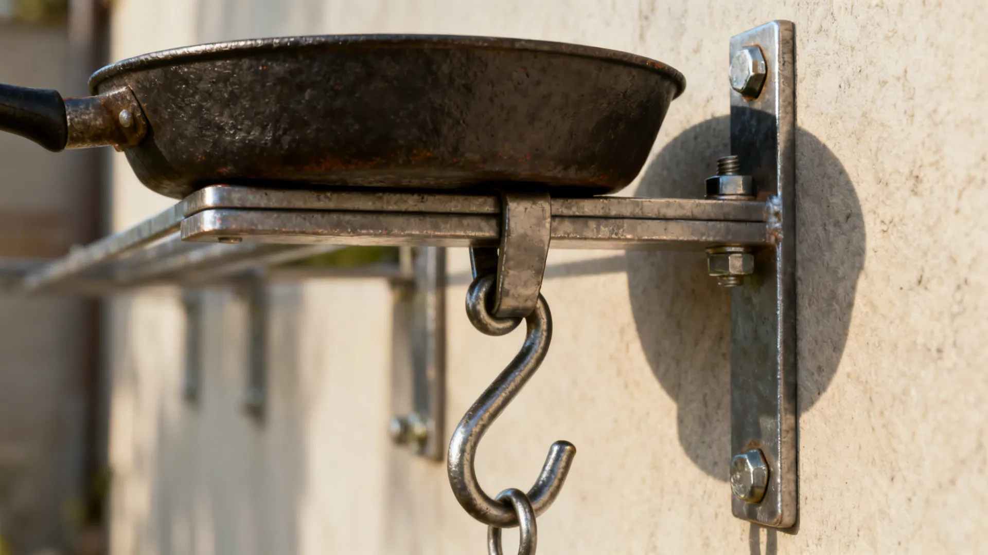 Close-up of a wall-mounted rail bracket and S-hook holding a cast-iron pan.