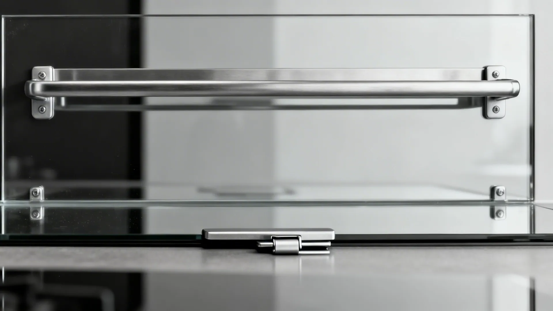 Close-up of a stainless utensil rail and reflective glass backsplash above a fold-down latch.