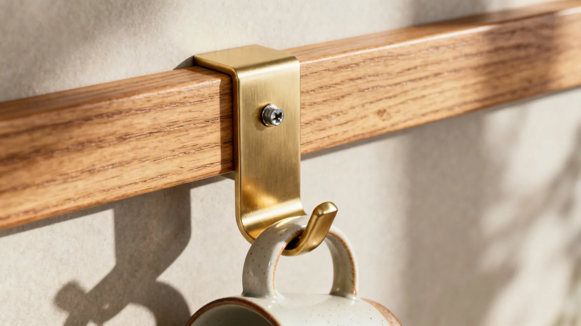 Close-up of brass rail bracket on an oak backer strip with a mug on a hook.