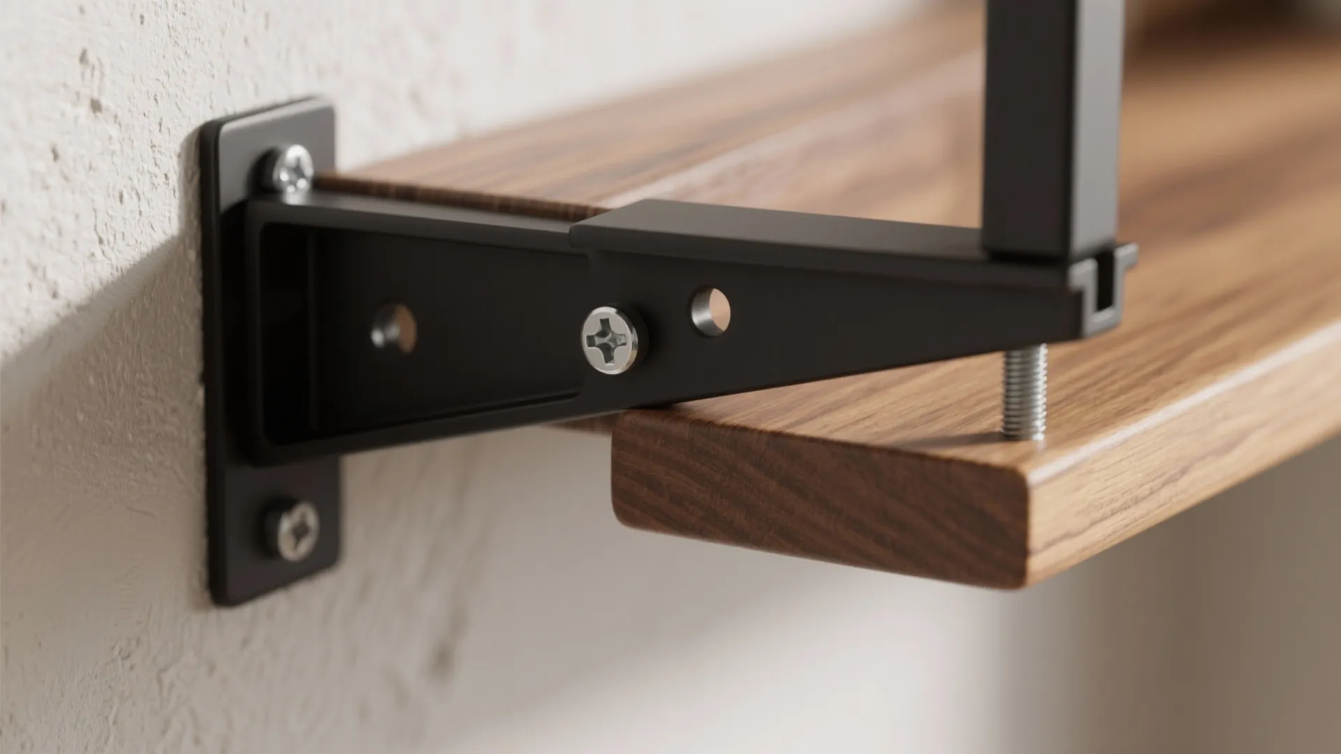 Macro of concealed bracket on 18 mm wood shelf meeting a matte black steel rail anchored to a stud.